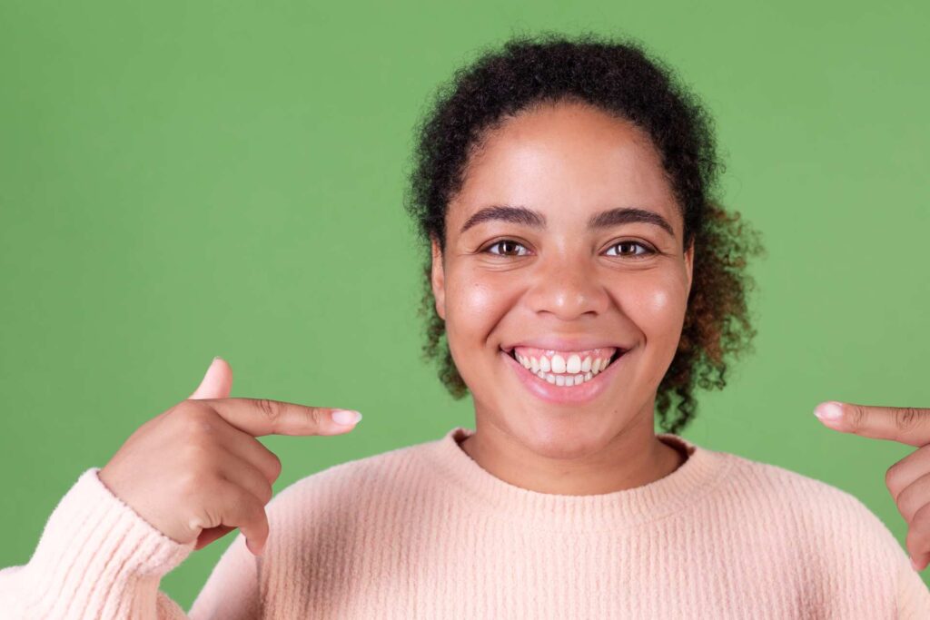 04 Mujer joven con sueter o jersey indicando su amplia sonrisa